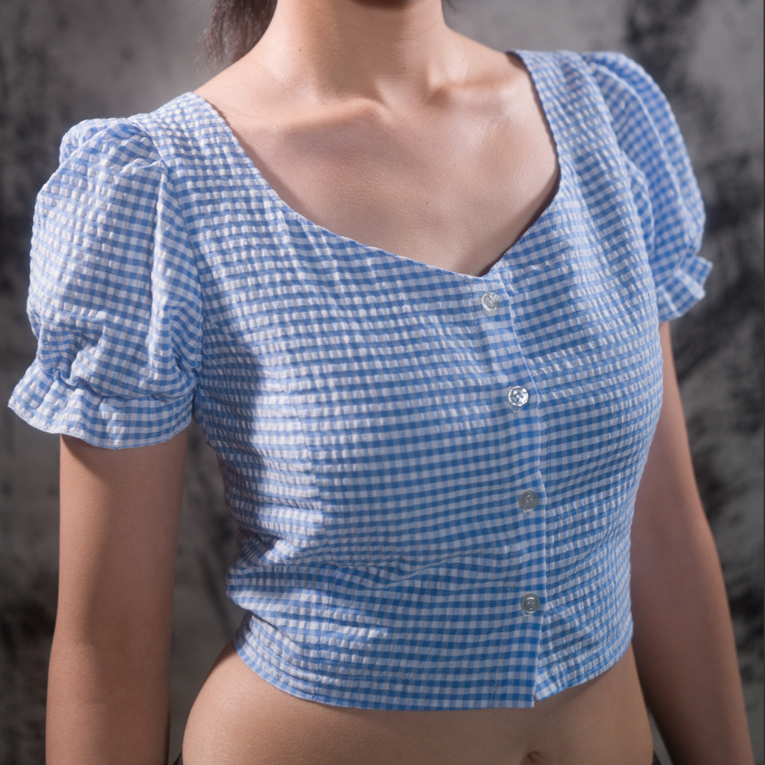Angled front view of model in blue gingham crop top