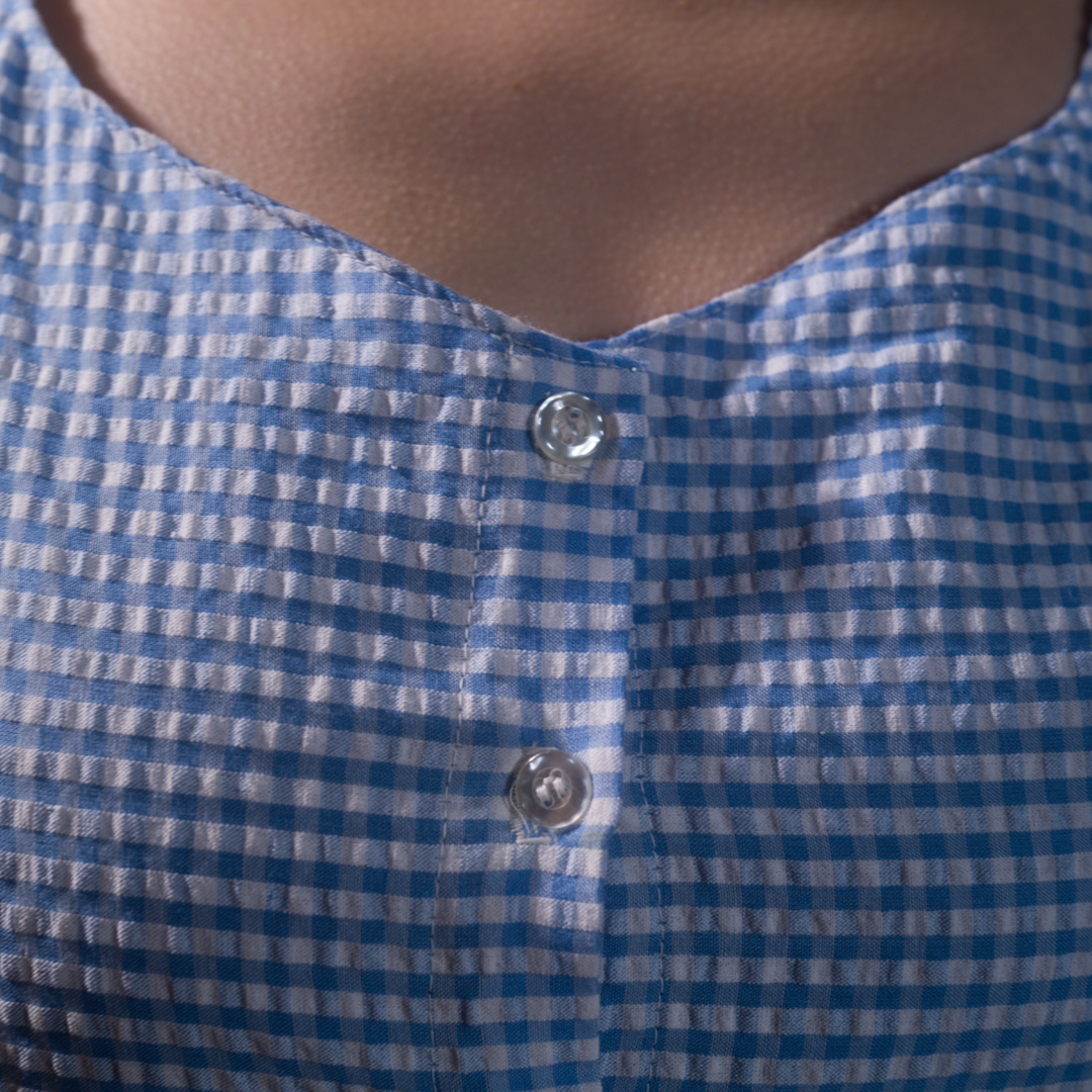 Button detail close-up on blue gingham cropped blouse