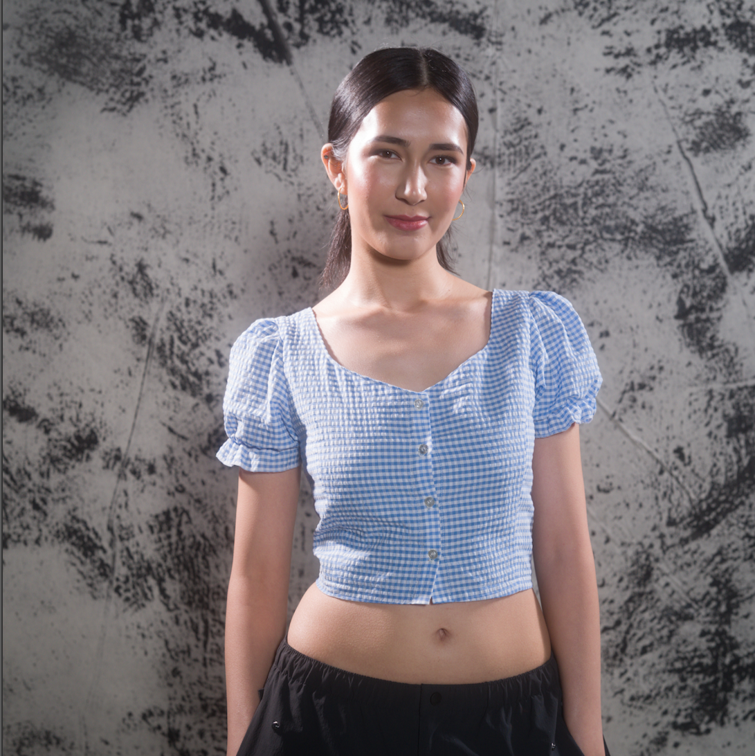 Woman wearing blue gingham crop top, front view with smile