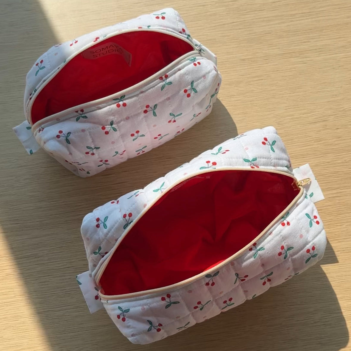Top-down view of small and medium cherry pouches opened to reveal vibrant red lining and roomy interior.