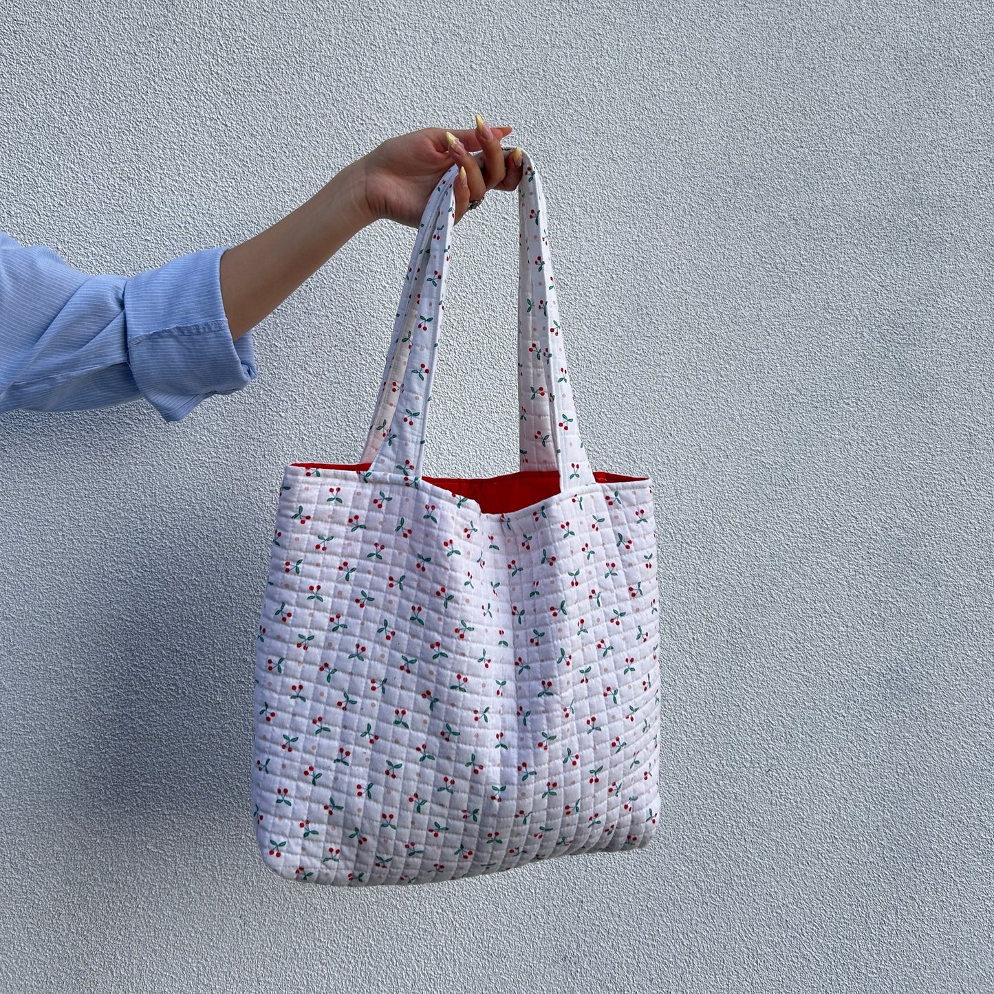 Back view of cherry print quilted tote bag showing strap and shape