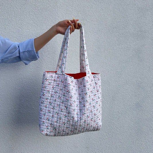 Back view of cherry print quilted tote bag showing strap and shape