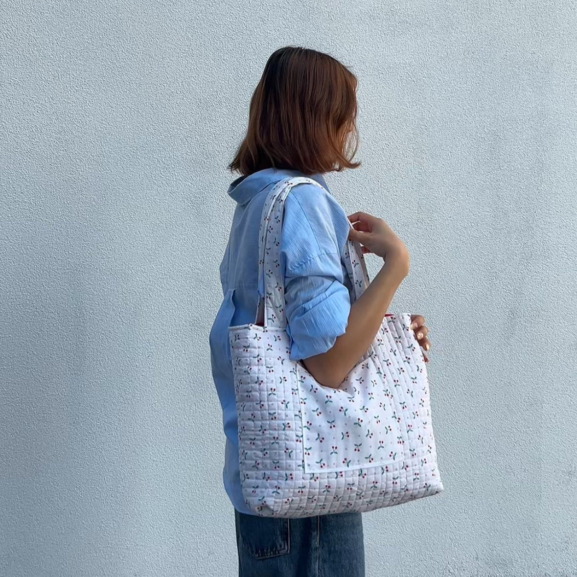 Model wearing cherry print quilted tote bag on shoulder