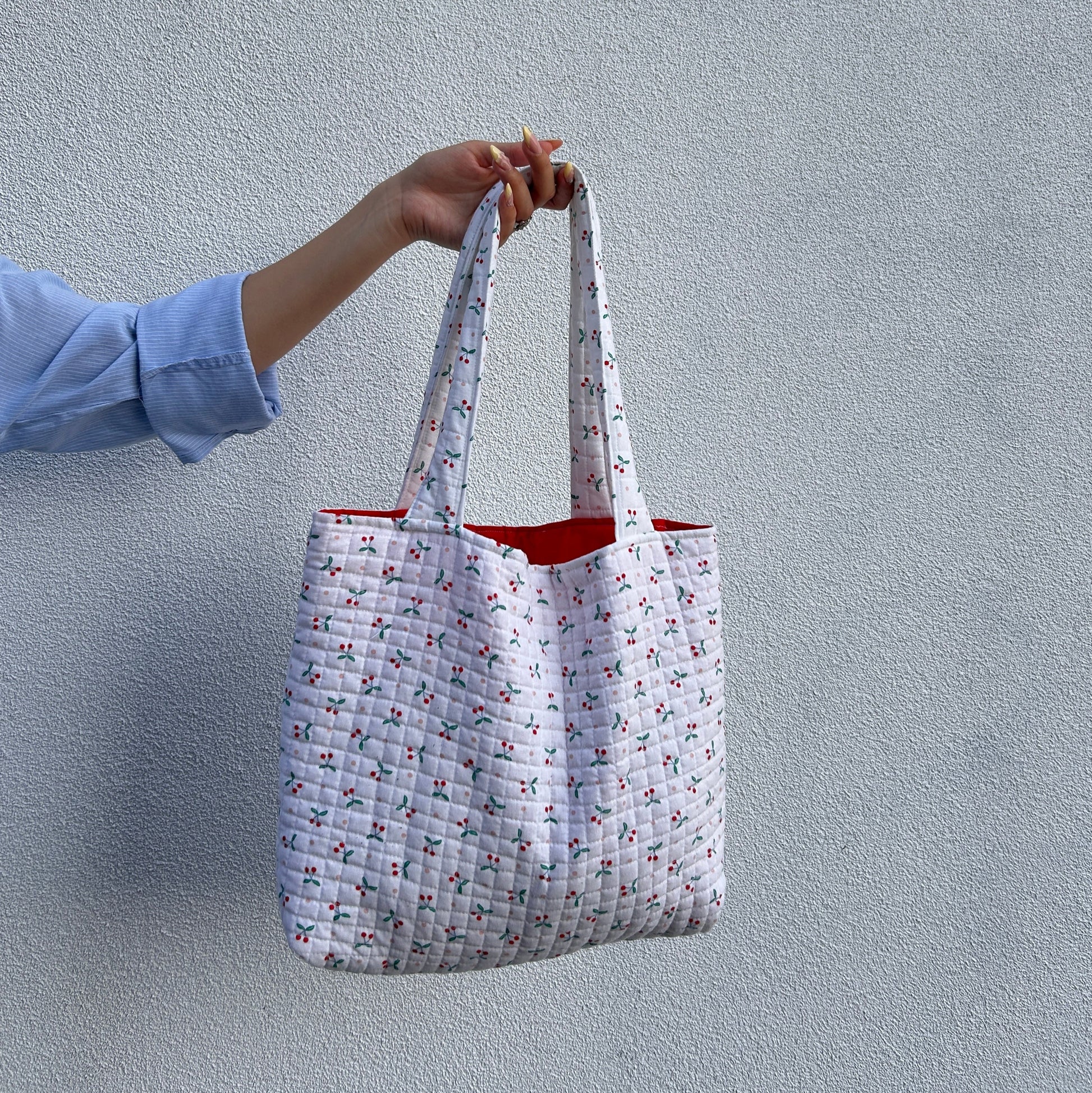 Back view of cherry print quilted tote bag showing strap and shape