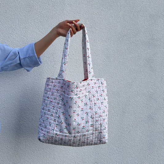 Front view of handmade quilted cherry print tote bag held by hand